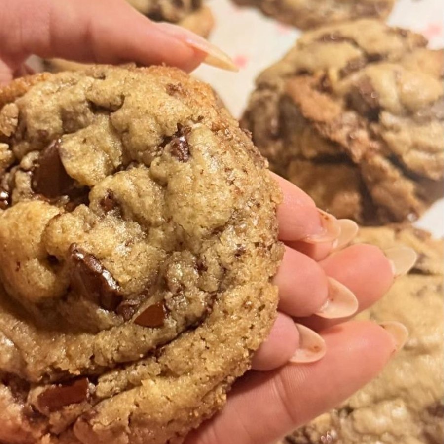 Galleta de chocolate recién horneada, sostenida en la mano
